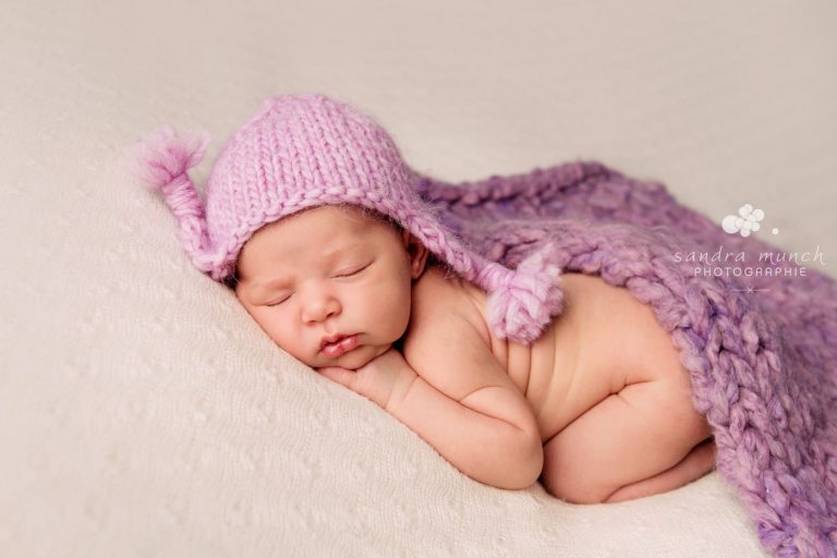 photo de bébé mignon couché sur le ventre avec bonnet péruvien mauve