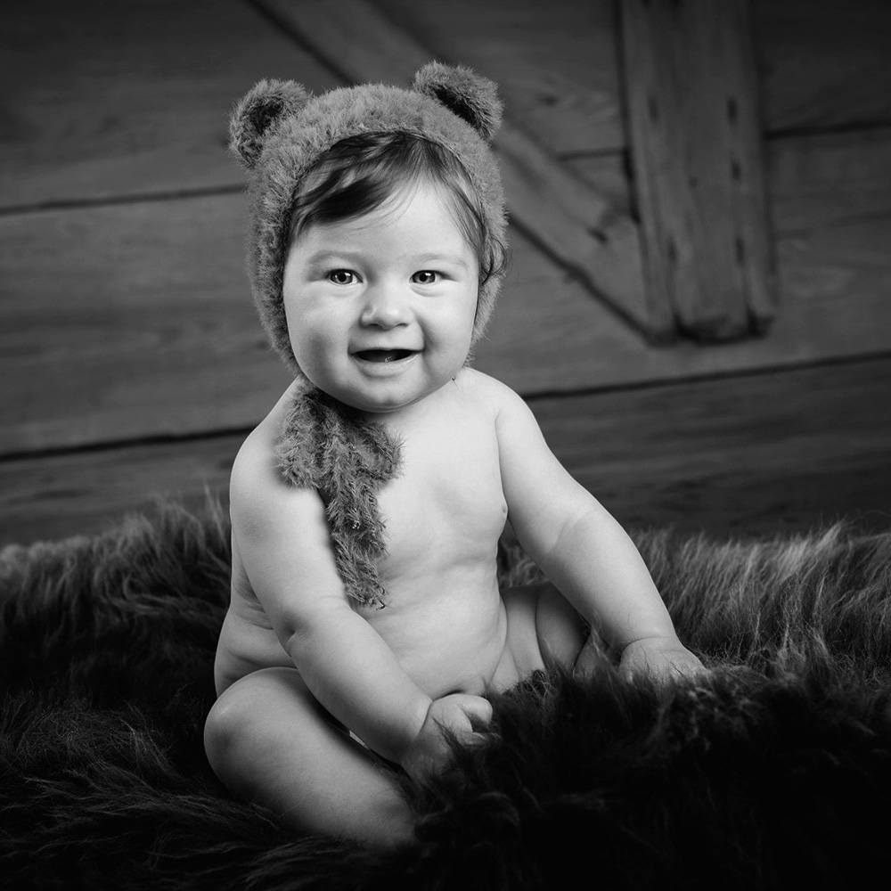 photo artistique de bébé espiègle de 6 mois assis avec un bonnet d'ours