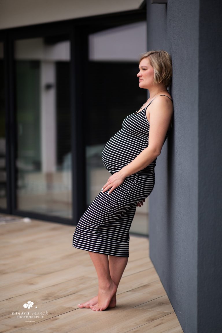 photo femme enceinte en robe rayée adossée à un mur gris anthracite