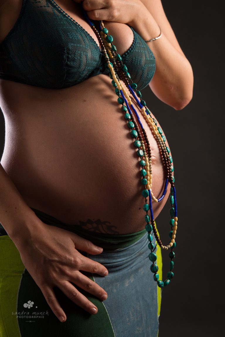 photo clair-obscure ventre de grossesse avec des colliers