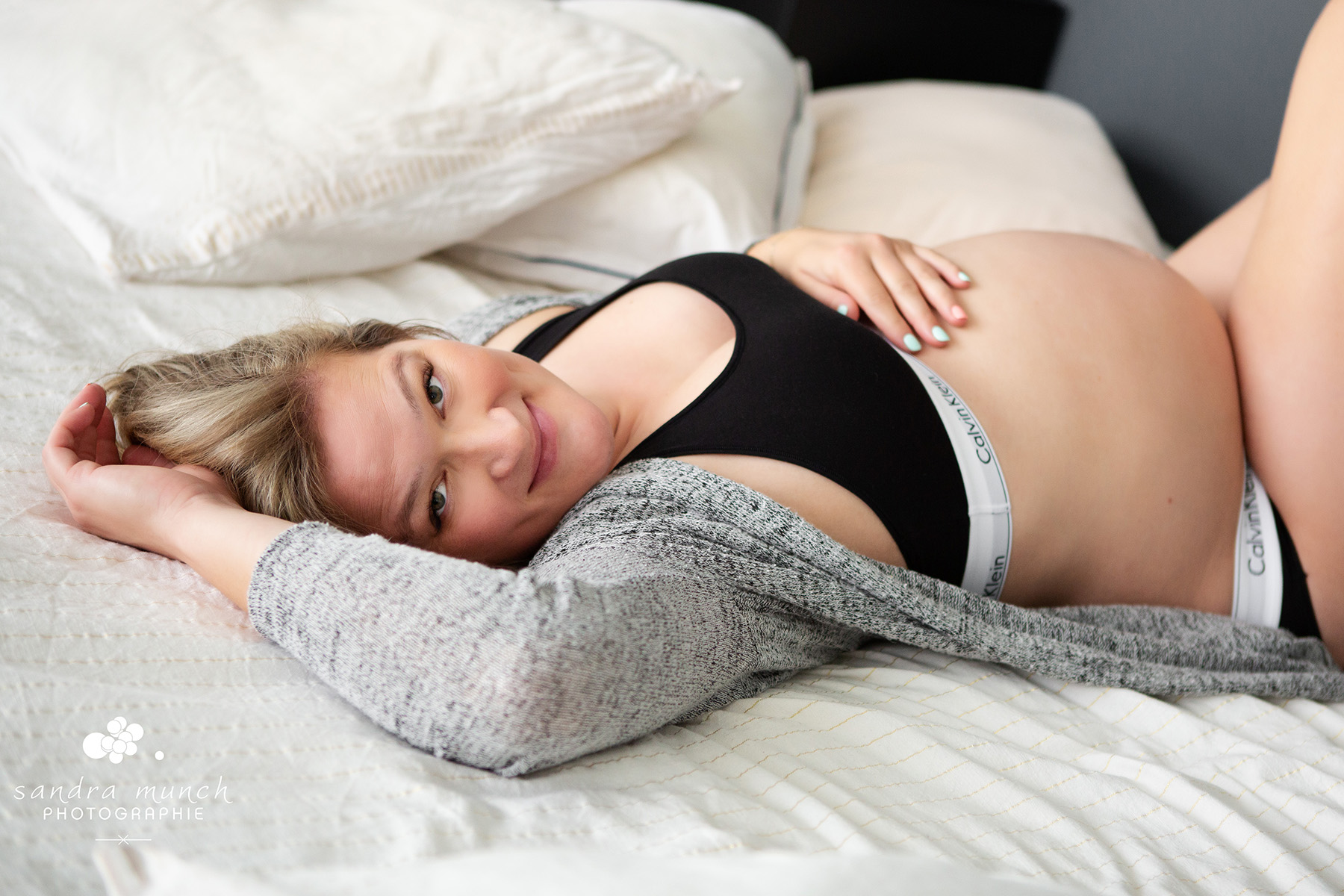portrait de femme enceinte allongée sur un lit style cocooning à domicile