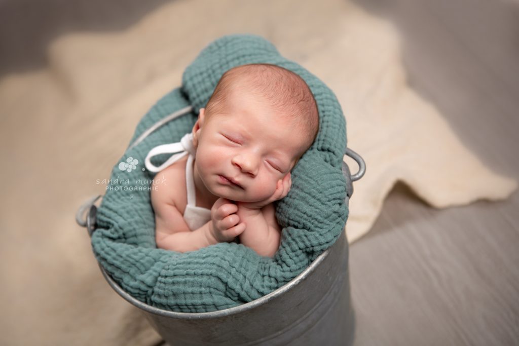 photo nouveau-né qui dort paisiblement dans un petit seau