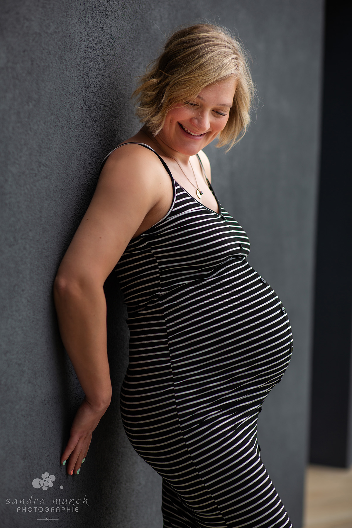 photo femme enceinte en robe adossée à un mur gris