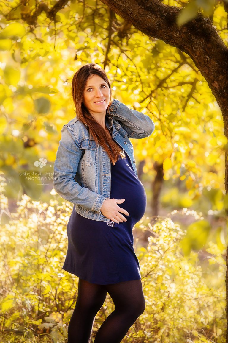 femme enceinte sous un arbre avec main sur le ventre