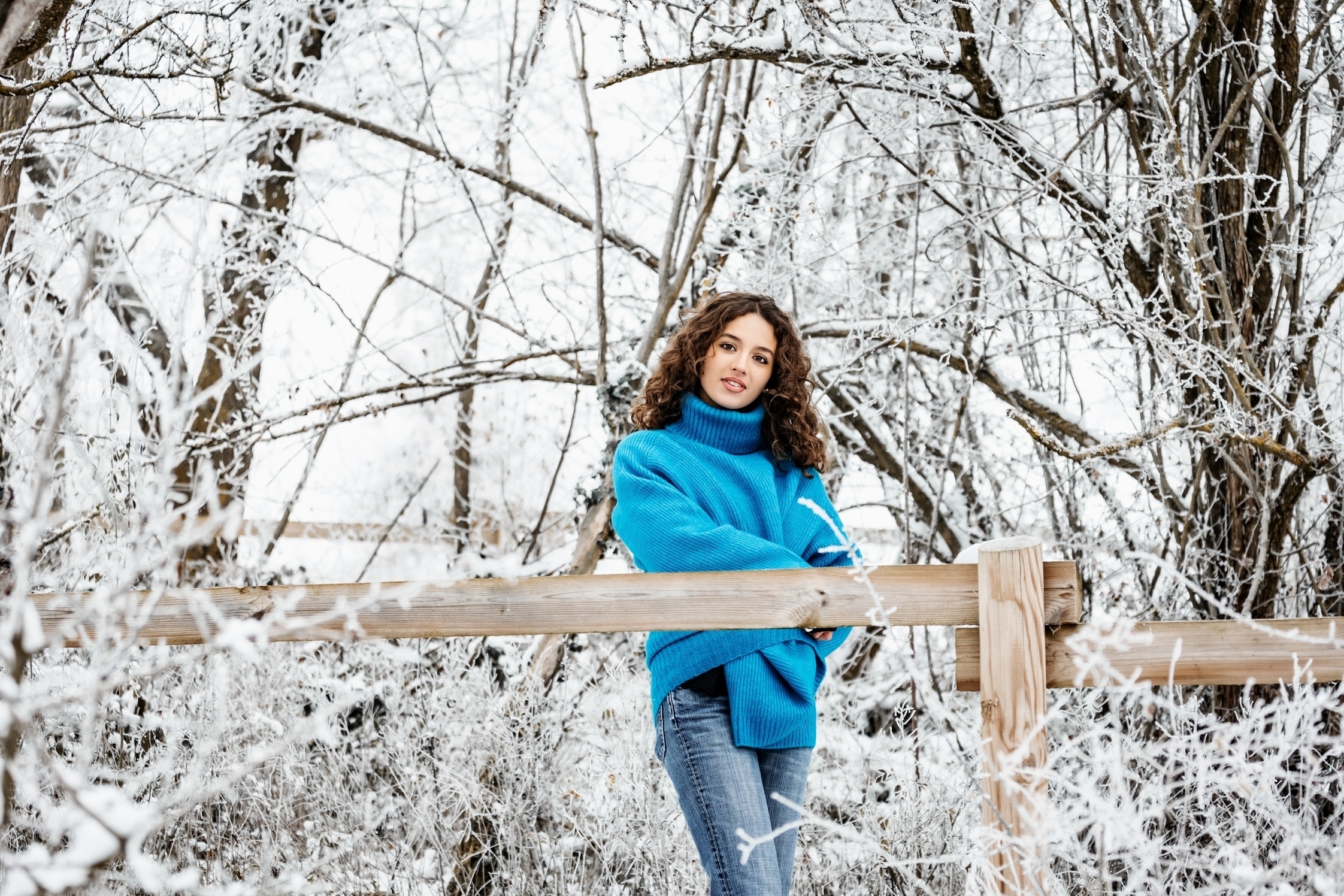 Jeune fille en pull bleu dans les bois enneigés