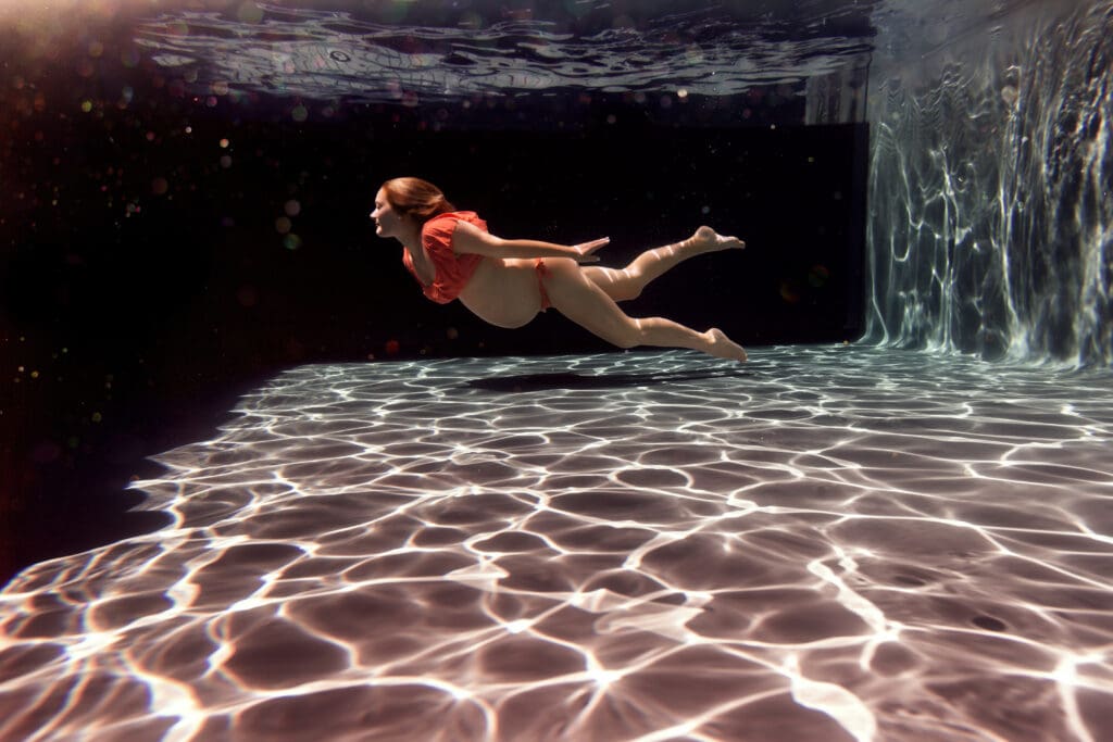 future maman dans la piscine vue de dessous la surface à domicile en Alsace