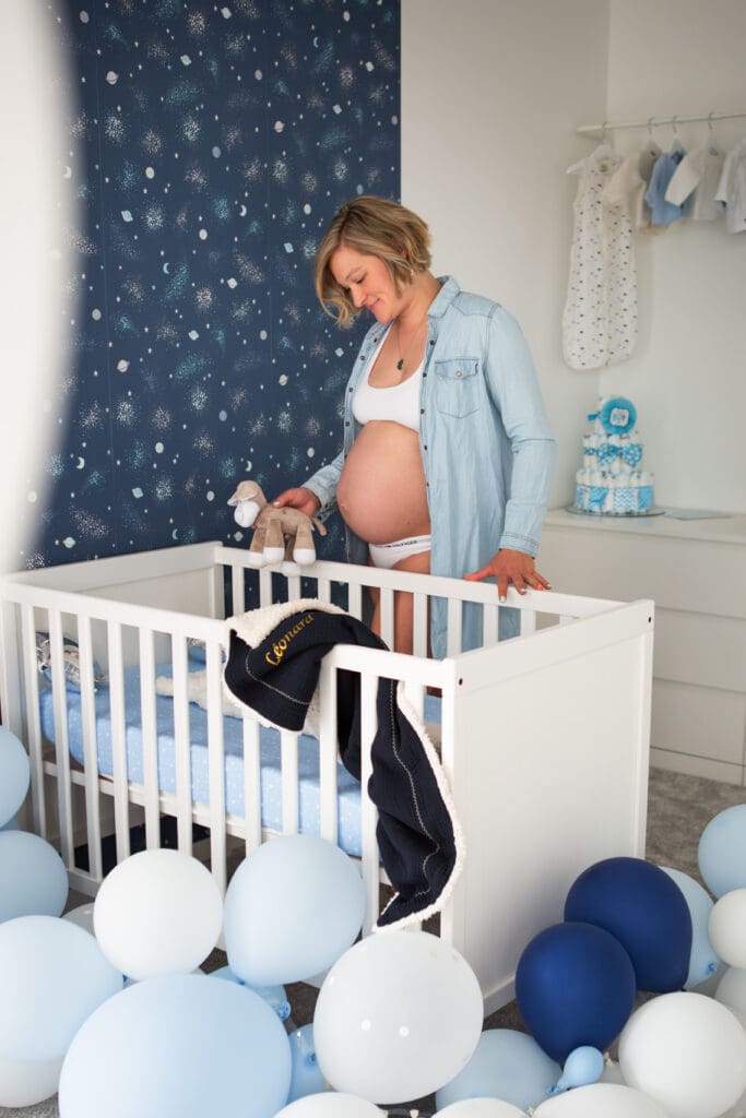 future maman regardant le petit lit de bébé lors d'une séance photo grossesse cocooning en Alsace