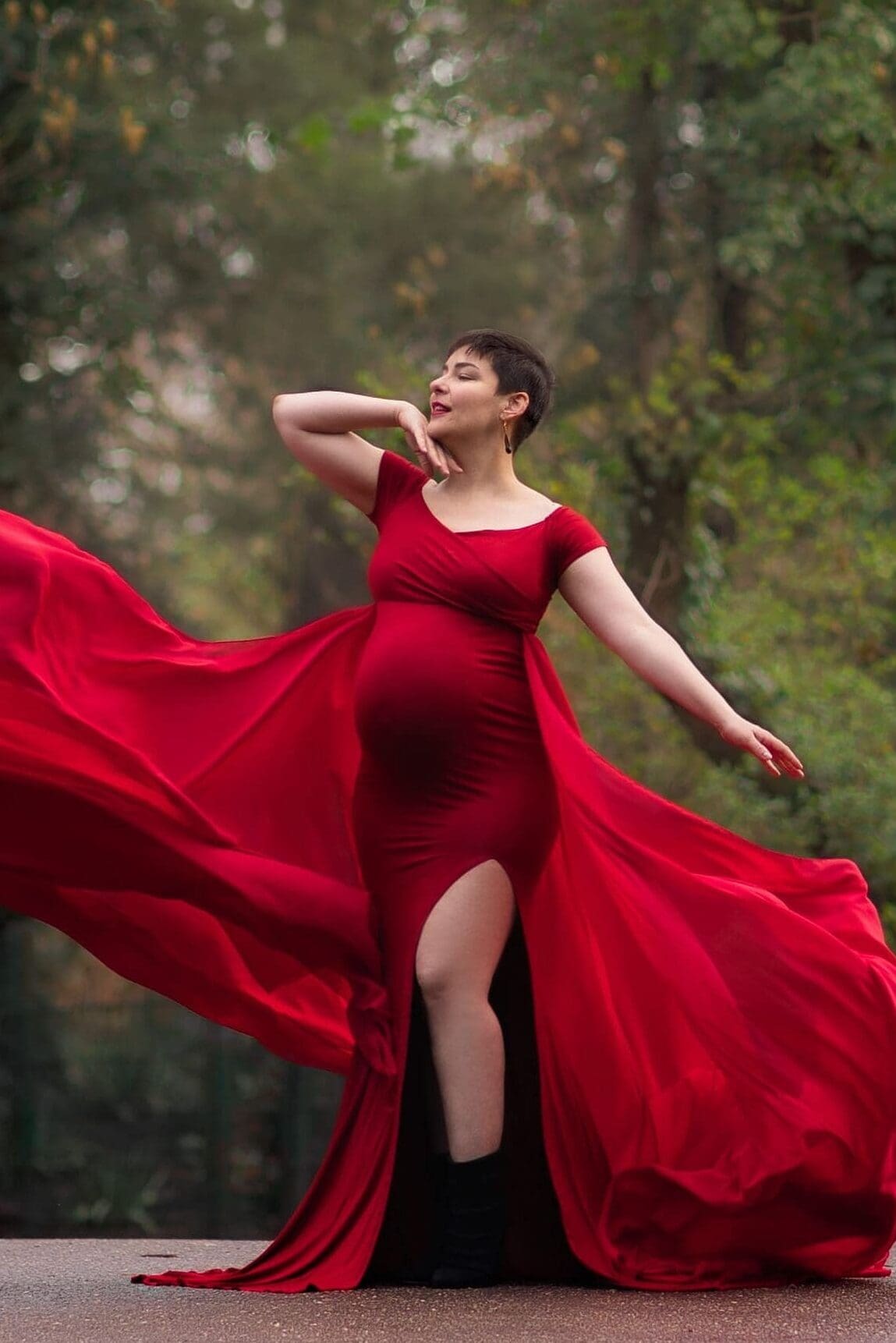 Future maman en robe rouge et voile fluide pour photos dans un parc à Strasbourg